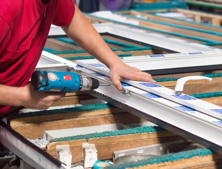 production of pvc windows, the worker is screwed with a screwdriver with a snap to the pvc window, close up, screwdriver
